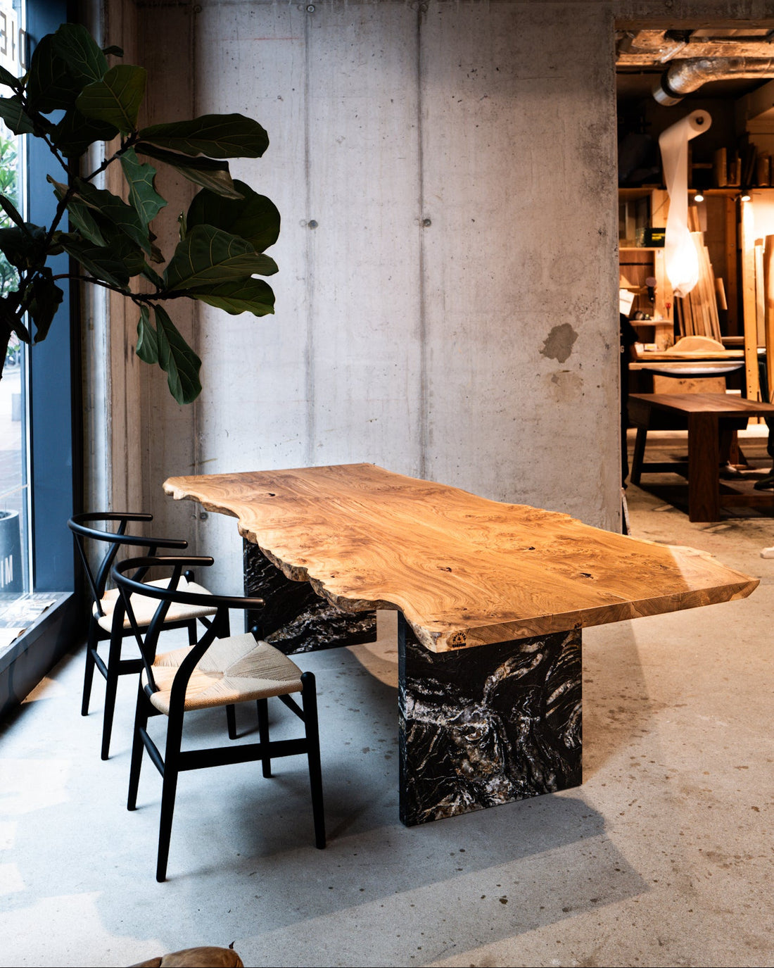 Baumtisch Eiche mit Naturkante auf Naturstein-Gestell im Showroom HafenCity | Holzwerk Hamburg