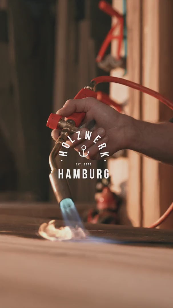 Geköhlte Eiche bei Holzwerk Hamburg: Platte wird mit dem Brenner geköhlt, schwarze Maserung, fertiger schwarzer Esstisch im Showroom.